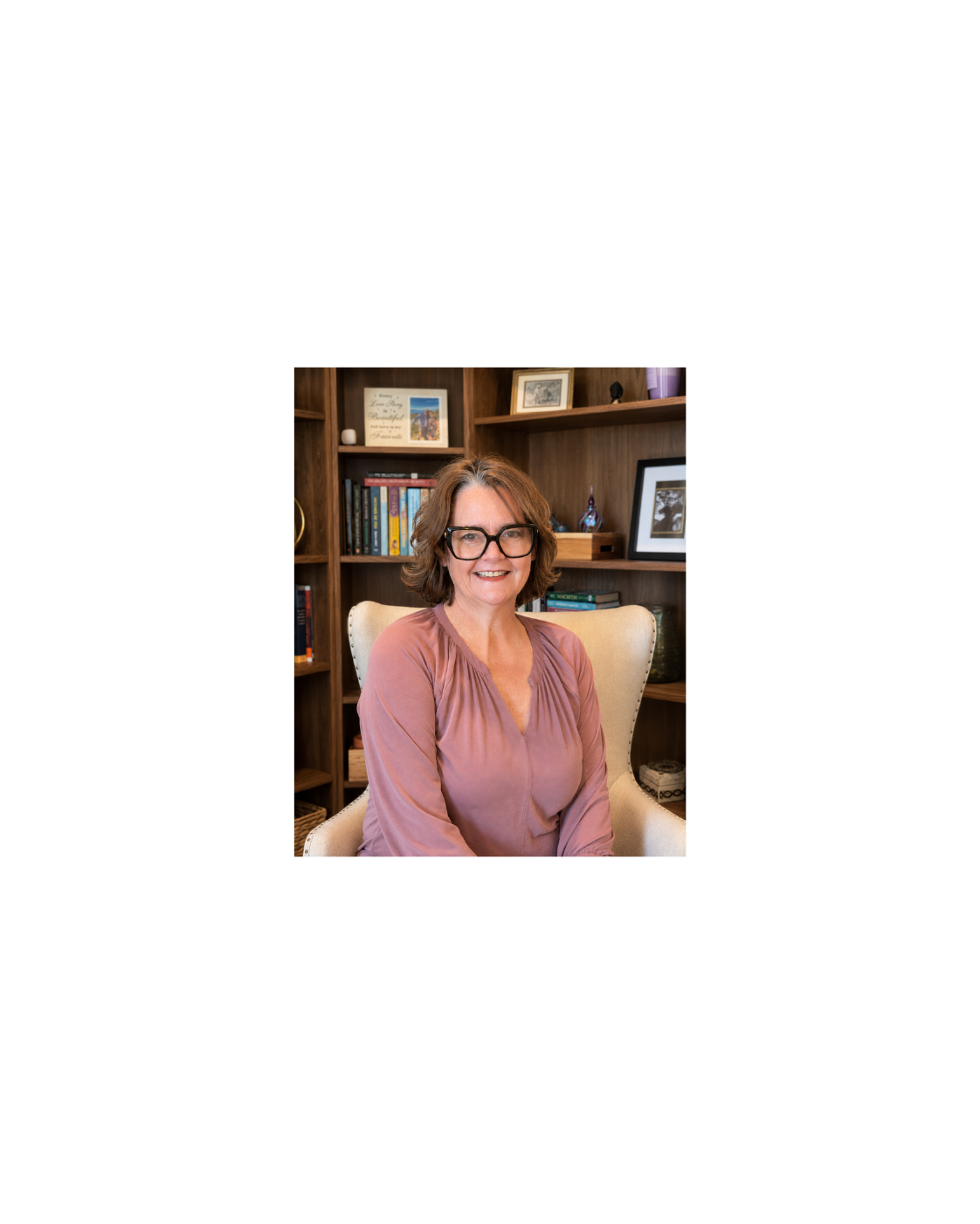 Dr. Susan Olsen seated in a chair in her home library
